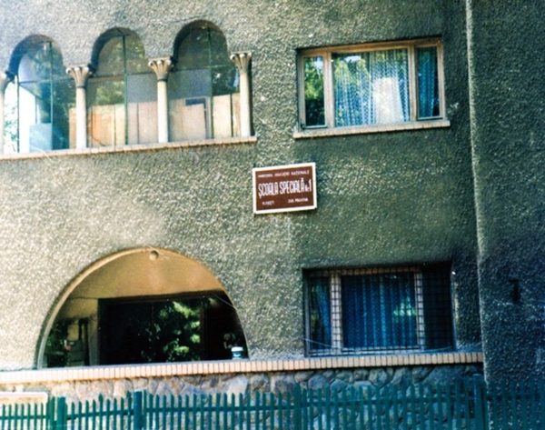 Fațada primei clădiri a școlii speciale, cu placa instituției la intrare